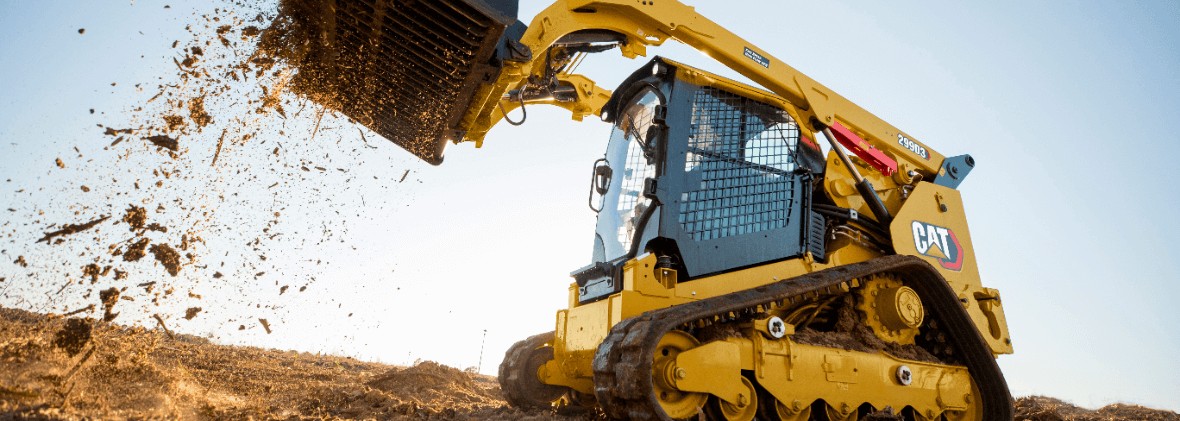 Caterpillar skid steer loader by Eltrak moving on-site while throwing dirt at a construction area.