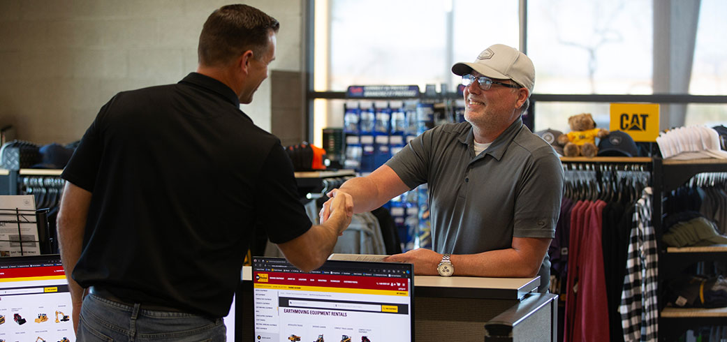 two men in a rental retail store shaking hands over the counter