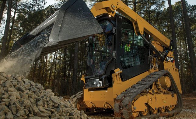 Compact track loader lifting dirt